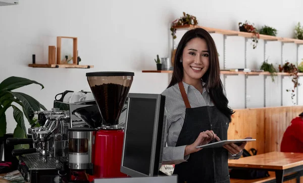 Alegre jovem asiático mulher proprietário segurando digital tablet enquanto em pé no seu café, jovem empreendedor conceitual — Fotografia de Stock