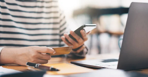 Online payment, womens hands holding a credit card and using smart phone for online shopping at home office — Foto de Stock