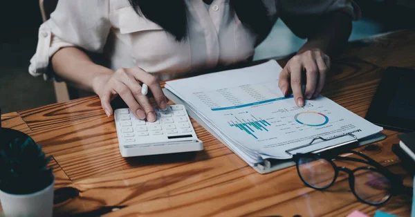 Affärskvinna arbetar på skrivbord med miniräknare med ekonomisk diagram rapport i ämbetet. begreppsbokföring. — Stockfoto