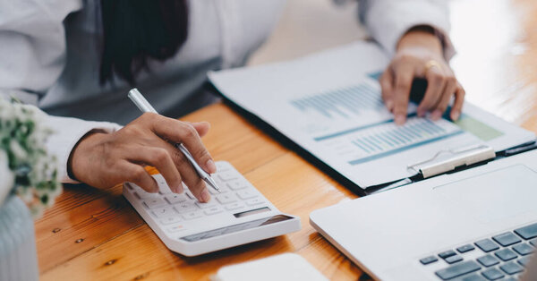 Close up hand of business woman accountant calculating budget of the company with calculator, Chart Graph Analysis