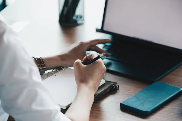 Cropped of woman hand taking notes with laptop at the table office — Stock Photo, Image