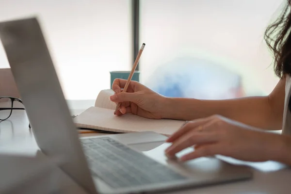 Cerca de las manos de las mujeres con el ordenador portátil, portátil y bolígrafo tomando notas en la oficina de negocios — Foto de Stock