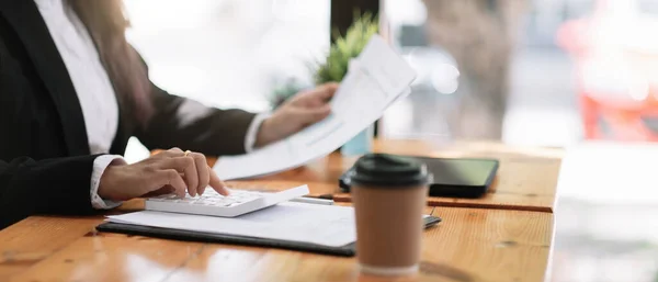 Accountant werkt op bureau met behulp van rekenmachine voor het berekenen van financiële rapport in cafe shop. — Stockfoto