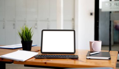 Boş beyaz ekranlı dijital tablet, klavye, çalışma masasında bir fincan kahve.