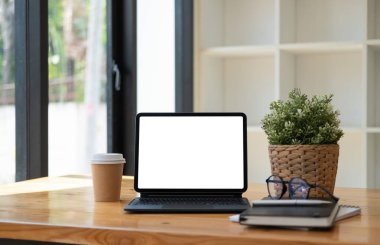 Boş beyaz ekranlı dijital tablet, klavye, çalışma masasında bir fincan kahve.