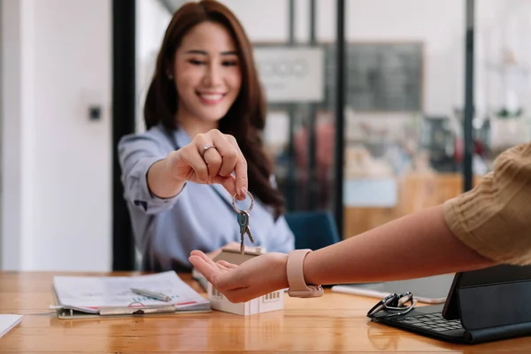 Cliente que toma llaves de agente de bienes raíces femenino durante la reunión después de firmar contrato de alquiler o contrato de compra de venta. Mujer independiente que compra casa nueva, vista de cerca. —  Fotos de Stock