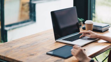 Dizüstü bilgisayardaki notları ve masadaki dijital tableti karşılaştıran öğrenci kız ellerini kapat. Kafede tablet kullanan kadın