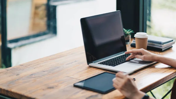 Gros plan des mains d'une étudiante comparant des notes sur un ordinateur portable et une tablette numérique assis sur un bureau. femelle utilisant la tablette au café — Photo