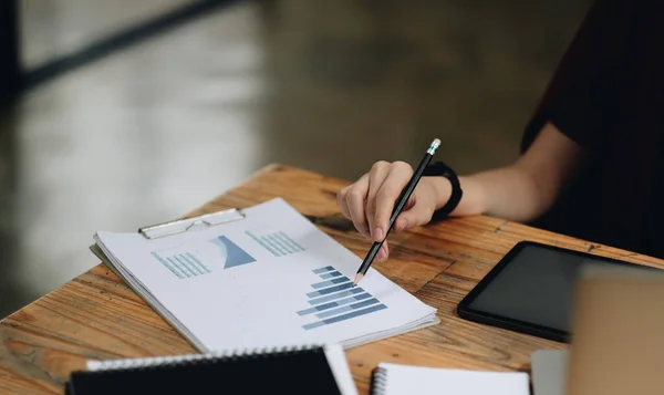 Närbild affärskvinna hålla penna och peka pappersdiagram sammanfattning analysera årliga affärsrapport med hjälp av laptop på rummet kontor skrivbord — Stockfoto