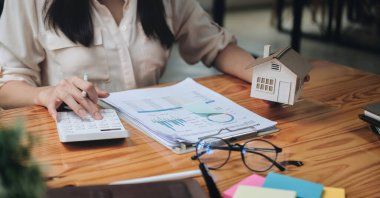 Ev modelinde finansman yapan ve emlak yatırımının maliyetini hesaplayan bir iş kadını ve diğer bir deyişle vergi sistemi. İş Finansmanı Muhasebe Bankacılık Konsepti