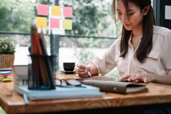 Nahaufnahme einer asiatischen Frau, die in ihrem Büro ein Tablet mit Stift benutzt. Geschäftliches Arbeitskonzept — Stockfoto