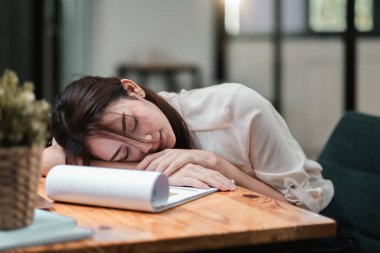 Tired and overworked business woman. Young exhausted girl sleeping on table during her work Entrepreneur, freelance worker or student in stress concept clipart