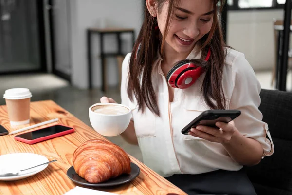 Mulher asiática usando fone de ouvido enquanto usa de telefone inteligentepara reunião online chamada de vídeo — Fotografia de Stock