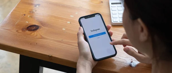 CHIANG MAI, THAILAND - SEP 5 2021: En kvinna håller Apple iPhone 12 med Instagram ansökan på skärmen på caféet. Instagram är en fotodelningsapp för smartphones. — Stockfoto