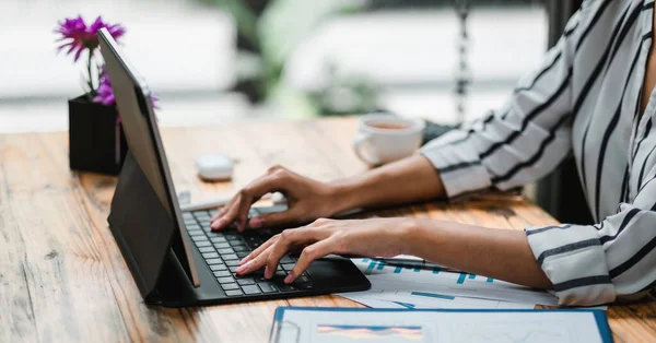 Gros plan des mains d'une étudiante comparant des notes sur une tablette numérique assise sur un bureau. femelle utilisant une tablette au café. concept de financement des entreprises. — Photo