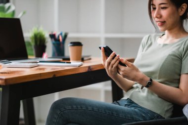 İş yerinde çalışan Asyalı bir kadının cep telefonu kullanması.