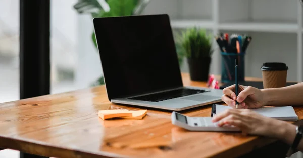 Close up of businessman or accountant hand holding pen working on calculator and laptop computer to calculate business data during make note at notepad, accountancy document at office. — Stock Photo, Image