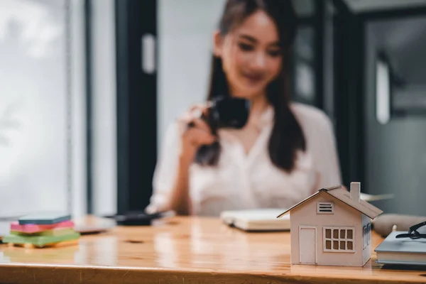 Real estate woman with house model on working desk for investment to buying property - selective focus at house model.