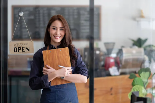 オープンサインボードで彼女のカフェカウンターの後ろに立つ笑顔のアジアの起業家の肖像 — ストック写真