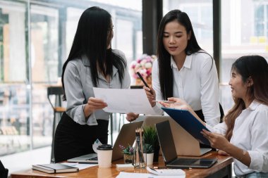 İş dünyasından Asyalı ekip finansal veriler ve pazarlama büyüme raporları ile birlikte şirket karından yararlanmak amacıyla strateji planlama, sunum ve beyin fırtınası grafiği üzerinde çalışmayı tartışıyor.