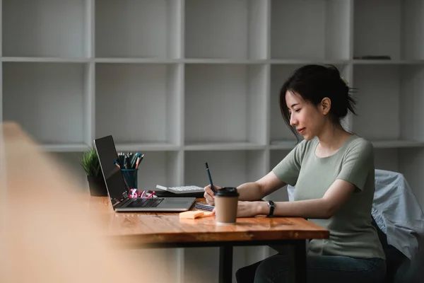 Beskuren bild av kvinna skriva gör lista med anteckningar i anteckningsblock arbetar eller lär sig på bärbar dator inomhus- utbildning kurs eller utbildning, seminarium, utbildning online koncept — Stockfoto