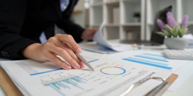 Bir iş analisti, modern ofis ortamında veri odaklı karar verme üzerine odaklanarak ayrıntılı mali raporlar ve grafikler inceler..