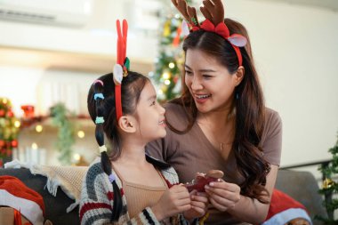 Ren geyiği boynuzu takan bir anne ve kız arasında neşeli bir alışveriş. Noel 'i sevgiyle ve kahkahalarla kutluyorlar..