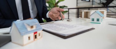 Bir emlakçı, emlak detaylarını ve seçenekleri tartışırken bir müşteriyle yakınlaşır, model evleri gösterir..