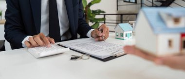 Bir gayrimenkul uzmanı, bir müşteriyle bilgilendirilmiş karar vermenin önemini vurgulayan bir emlak anlaşmasını gözden geçirir..