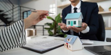 Bir emlakçı müşterisine örnek evler sunar, gayrimenkul detaylarını ve yatırım fırsatlarını profesyonel ortamlarda tartışır.