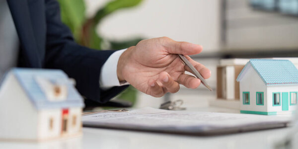 A real estate professional shows model houses to a client during a consultation, discussing property choices and investment.