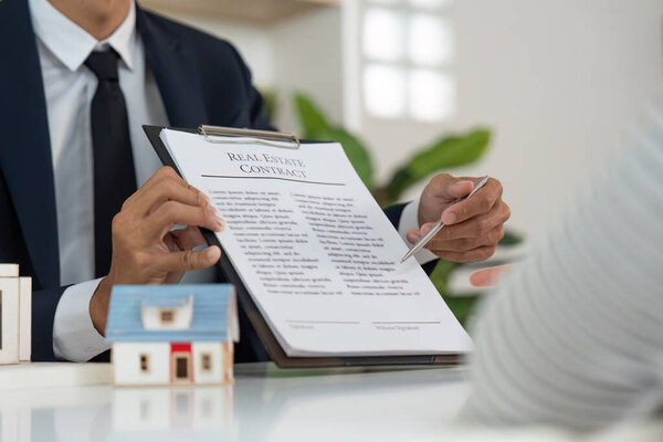 A real estate agent discusses a contract with a client, showcasing professionalism in a modern office setting.