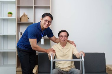 Bakıcı yaşlı bir adama yürüteçle yardım eder, destekleyici bir ev ortamında güvenlik ve konfor sağlar..