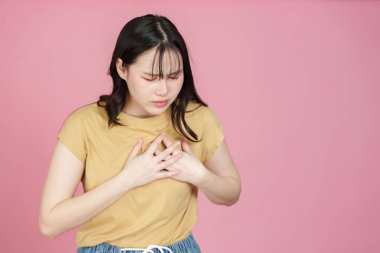 Göğsünü tutan endişeli bir ifadeyle genç bir kadın, sağlık ve duygusal sağlığın farkında olduğunu gösteriyor..