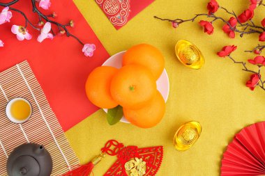 Çin Yeni Yılı için portakal, kırmızı zarf ve altın külçeler, zenginlik ve mutluluğu temsil eden renkli düzenlemeler..