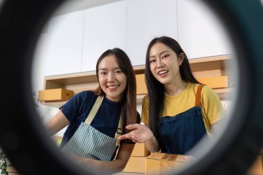 E-ticaret ambalaj alanında çalışırken gülümseyen ve arkadaş canlısı iki kadın. İşbirliği ve pozitiflik kavramı.