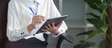 Profesyonel bir kadın tabletle meşgul oluyor, bitkilerle dolu şık bir ofis alanı planlıyor..