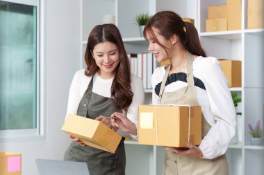 E-ticaret görevlerinde işbirliği yapan, modern ofis ortamında siparişleri ve ambalaj ürünlerini yöneten iki kadın.