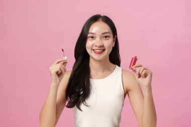 Neşeli bir kadın dudak parlatıcısı ve ruj tutar, canlı dudak bakımı ve makyaj tercihlerini teşvik eder..