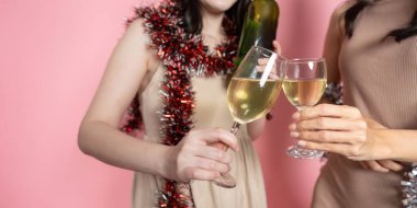 Şampanya kadehleriyle kadeh kaldıran iki arkadaşın canlı bir atmosferde kutlama yaptıkları yakın plan bir fotoğraf. Parti temaları için mükemmel.