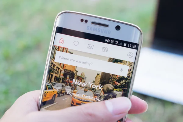 CHIANG MAI, TAILANDIA - 21 DE NOV DE 2015: Un hombre sosteniendo la captura de pantalla de Airbnb en Samsung Galaxy S6 edge. una plataforma en línea para alojamiento, búsqueda y alojamiento privado de alquiler a corto plazo en todo el mundo . — Foto de Stock