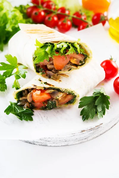 Mexican vegetable burrito wrap tomatoes, lettuce and mushrooms on white background, vegetarian food, close-up