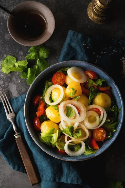 Boiled potatoes with onions and vegetables in a plate, traditional Russian dish, top view