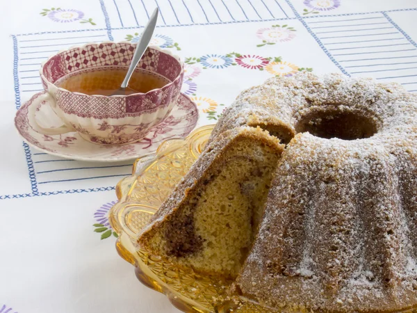 Pastel en un tazón de vidrio amarillo con una taza de té —  Fotos de Stock