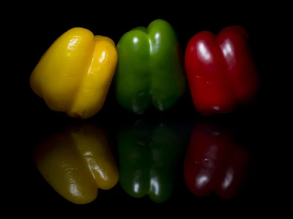 Siyah cam üzerinde sarı, yeşil ve kırmızı biber