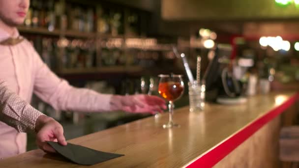 Sirviendo detalles. Retrato de un camarero profesional poniendo una copa con un cóctel en una servilleta en el bar — Vídeo de stock