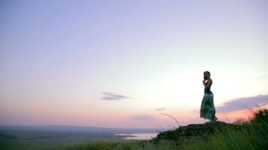 Young Woman Standing On The Rock. Evening Sky. Wide angle