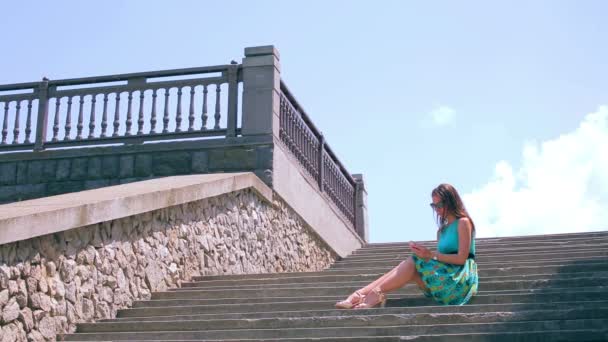 Attractive Girl Surfer sur Internet au téléphone assis sur de vieux escaliers. Grand angle — Video