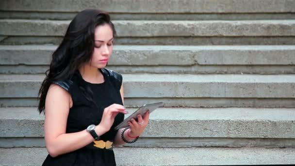 Atraktivní mladá bruneta sedí na schodech a textilie — Stock video