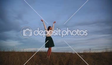 Genç bir kadın karşı akşam gökyüzünde dans ediyor